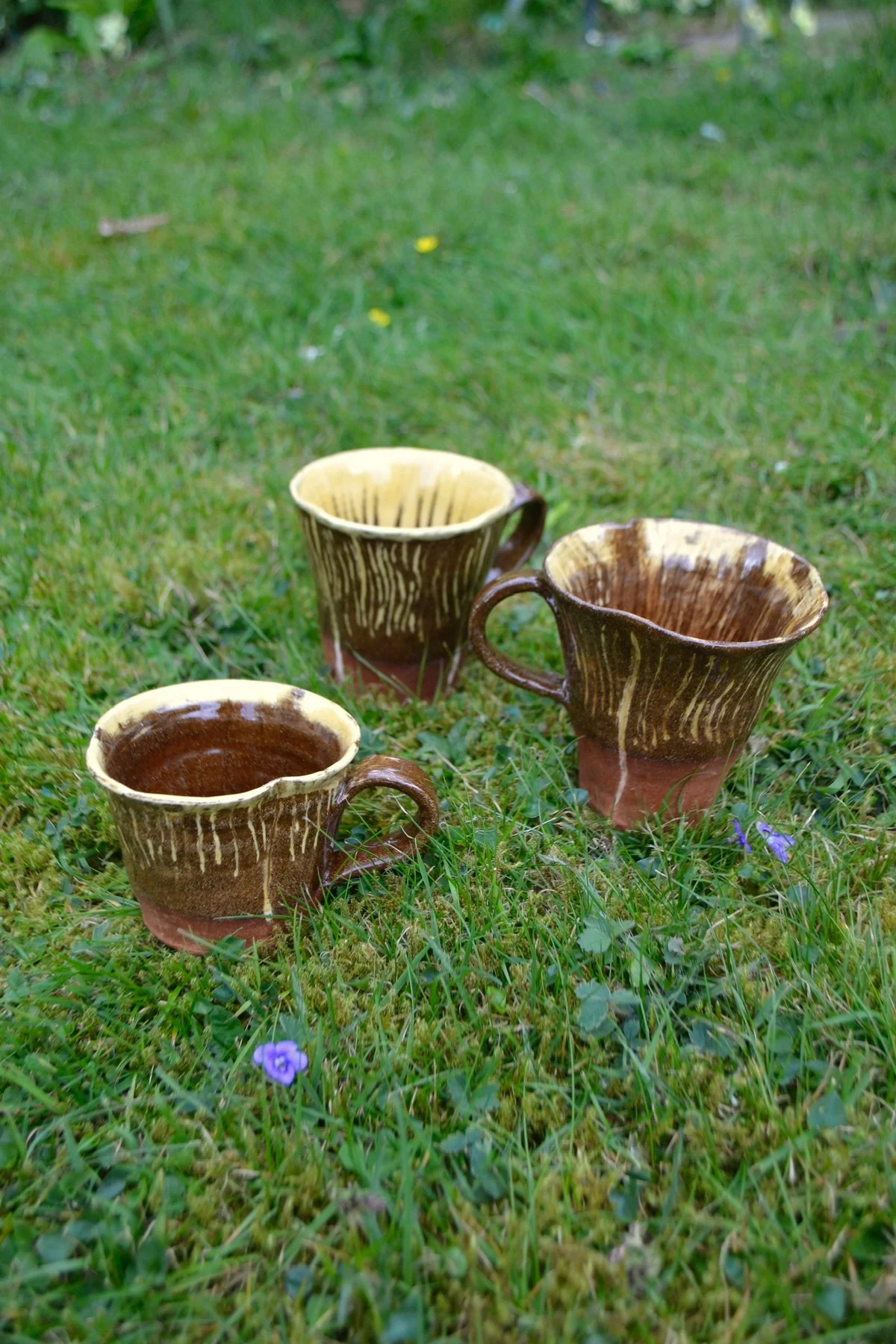 Three brown fungi-inspired mugs with ridged sides and curved handles.