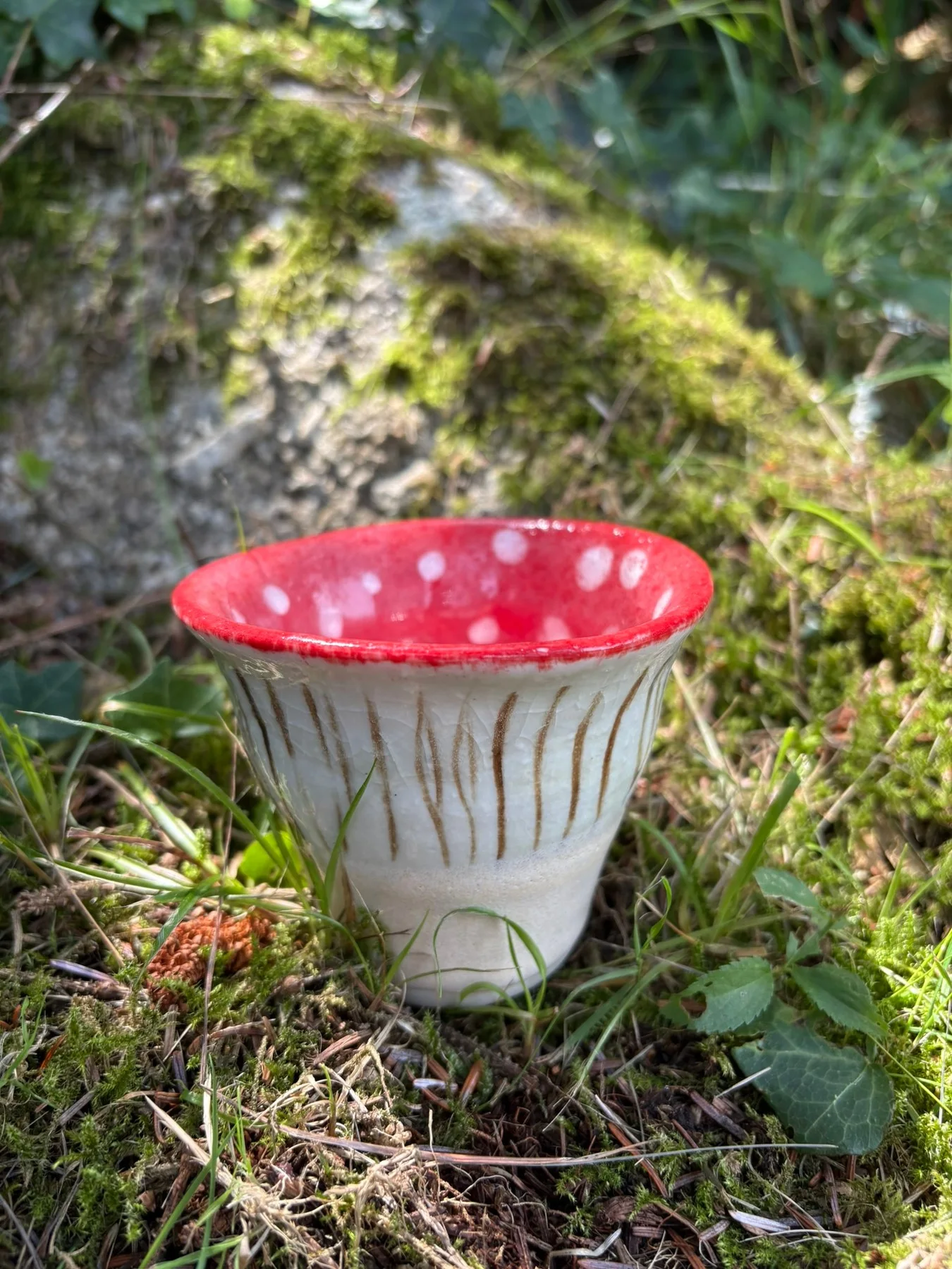 Fly Agaric vessel with a flared pale exterior, dark vertical streaks and a red interior.