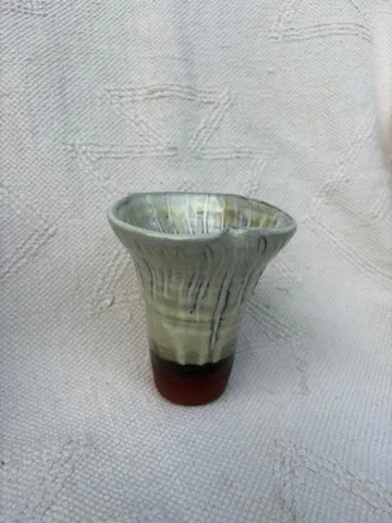 Green fungi-inspired vessel with an uneven flared rim and a brown base.