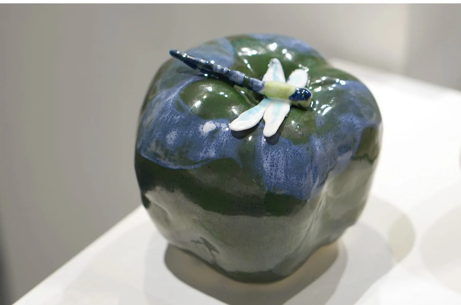 Blue and green porcelain apple with a small white flower.