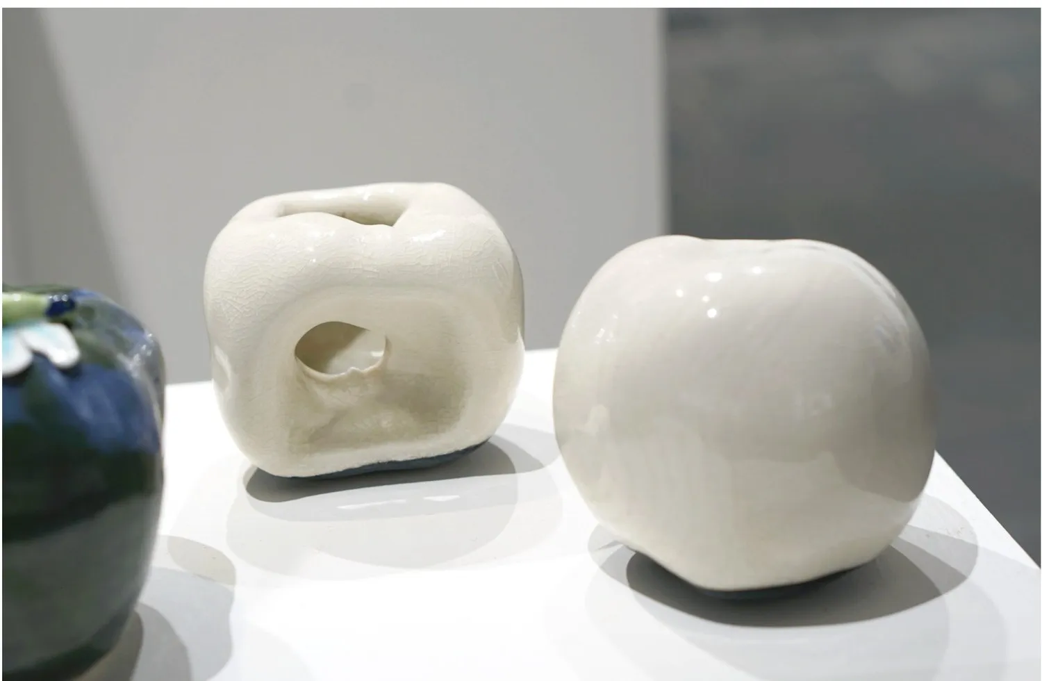 Two pale porcelain apple forms displayed together.