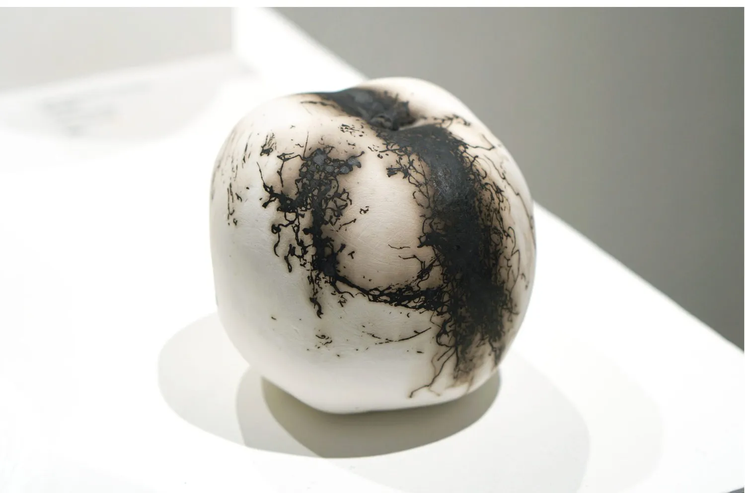 White porcelain apple with branching dark marks.