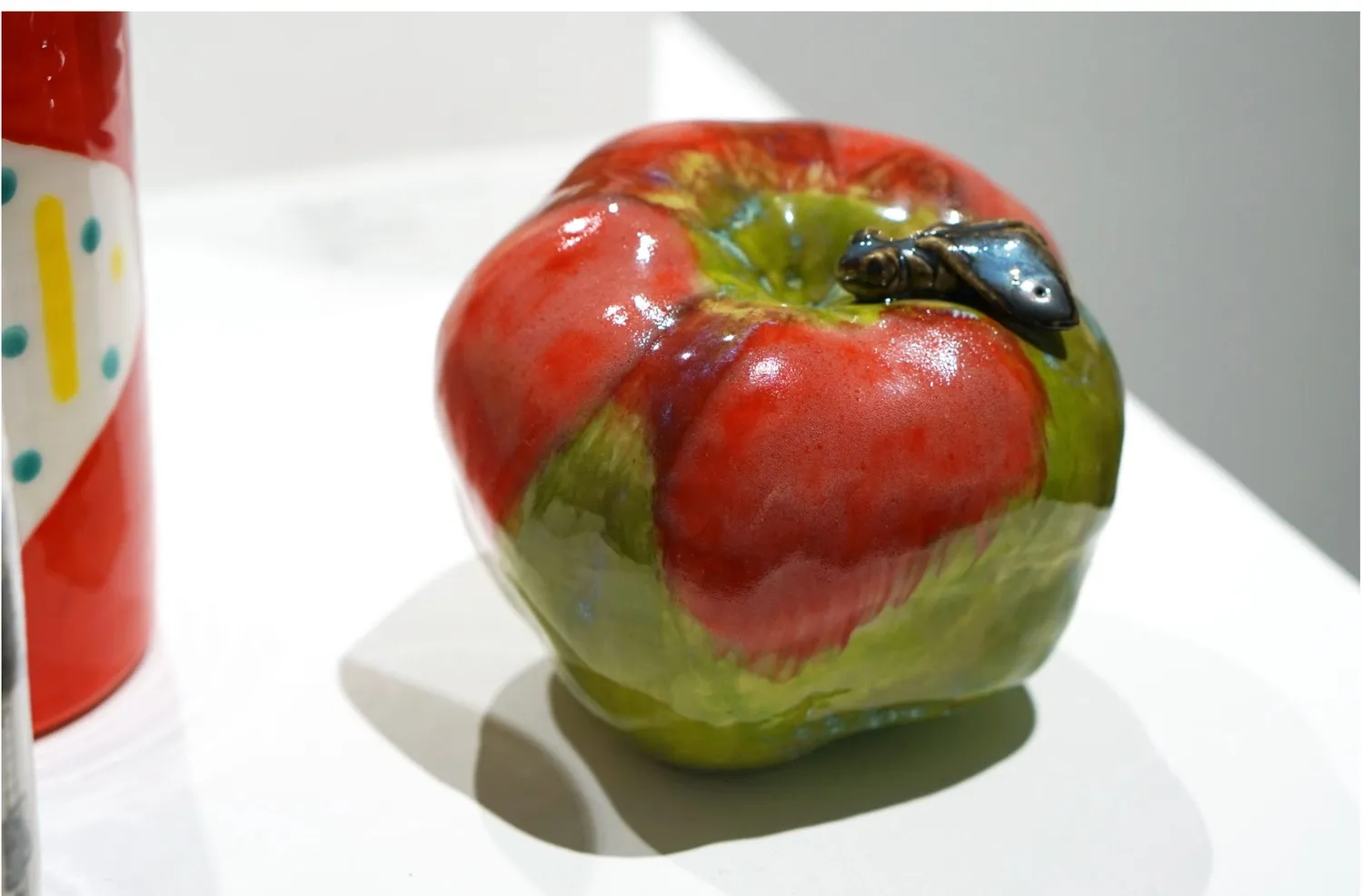 Red and green porcelain apple with a small insect.