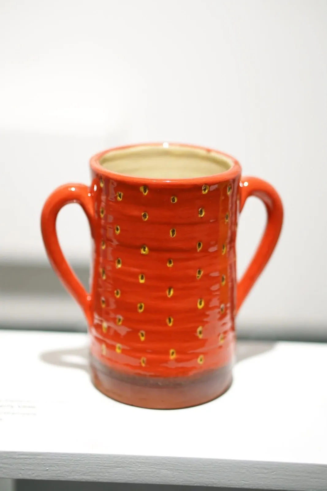 Tall red strawberry vessel with two handles.