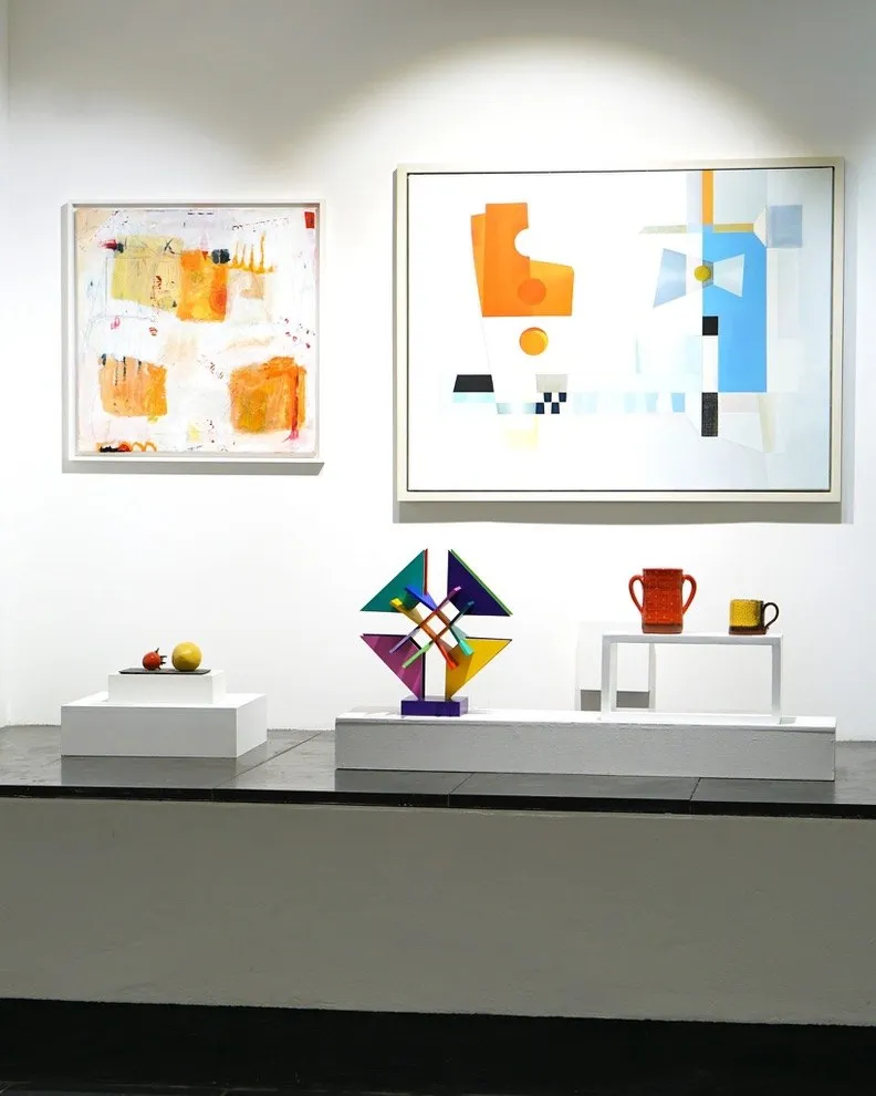 Gallery view with ceramics displayed beneath paintings.