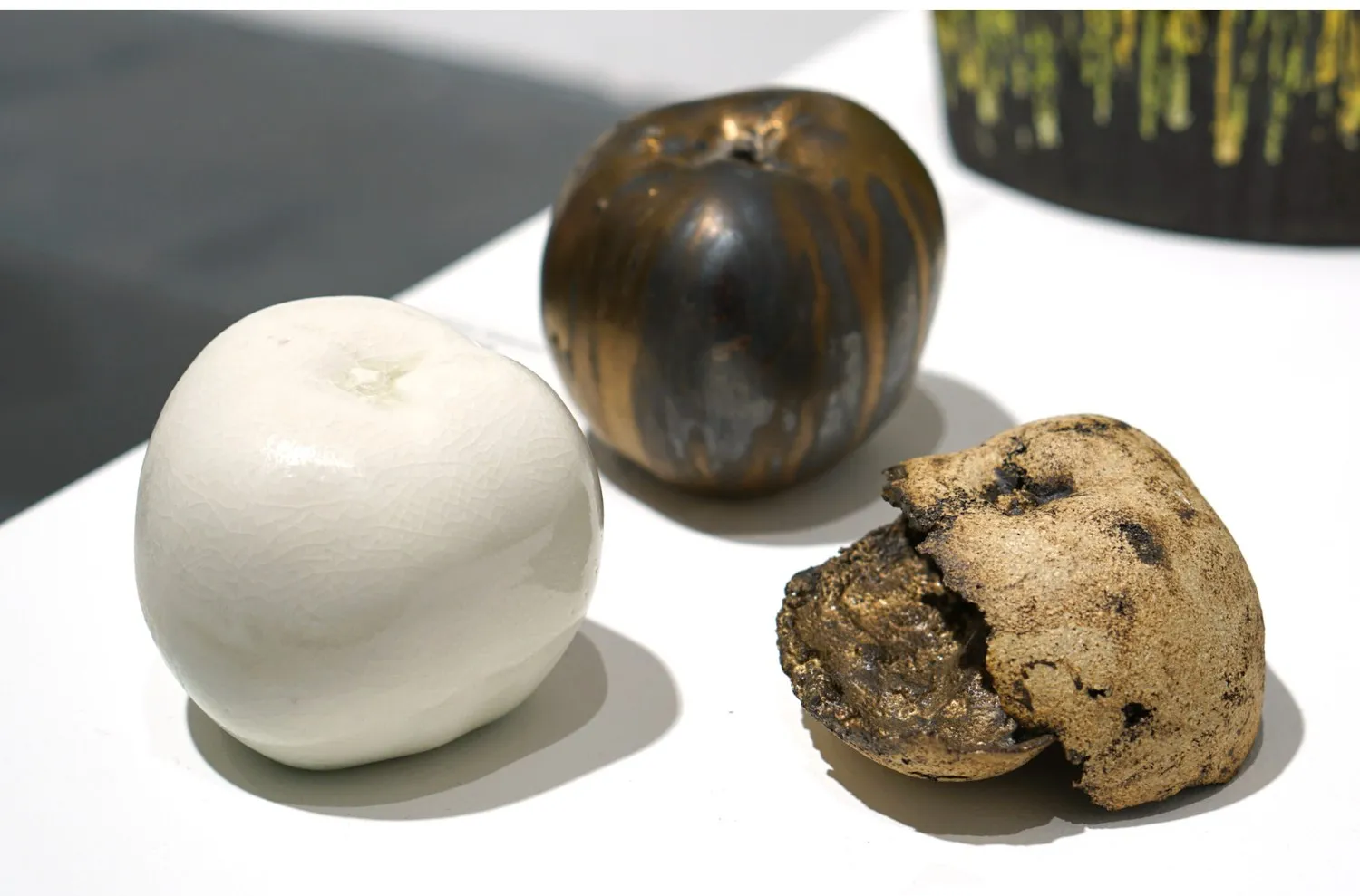 Three porcelain apples exploring different surfaces and states of decay.
