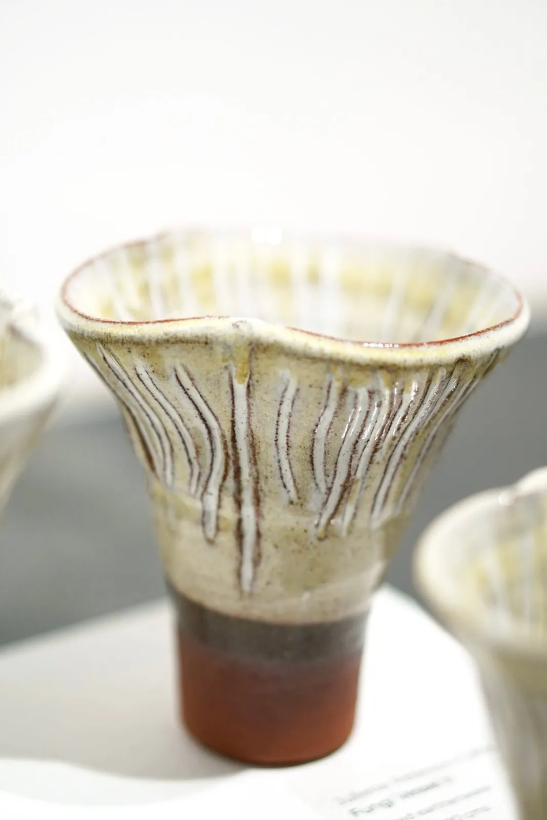 Tall ridged fungi vessel with pale glaze and a warm clay foot.