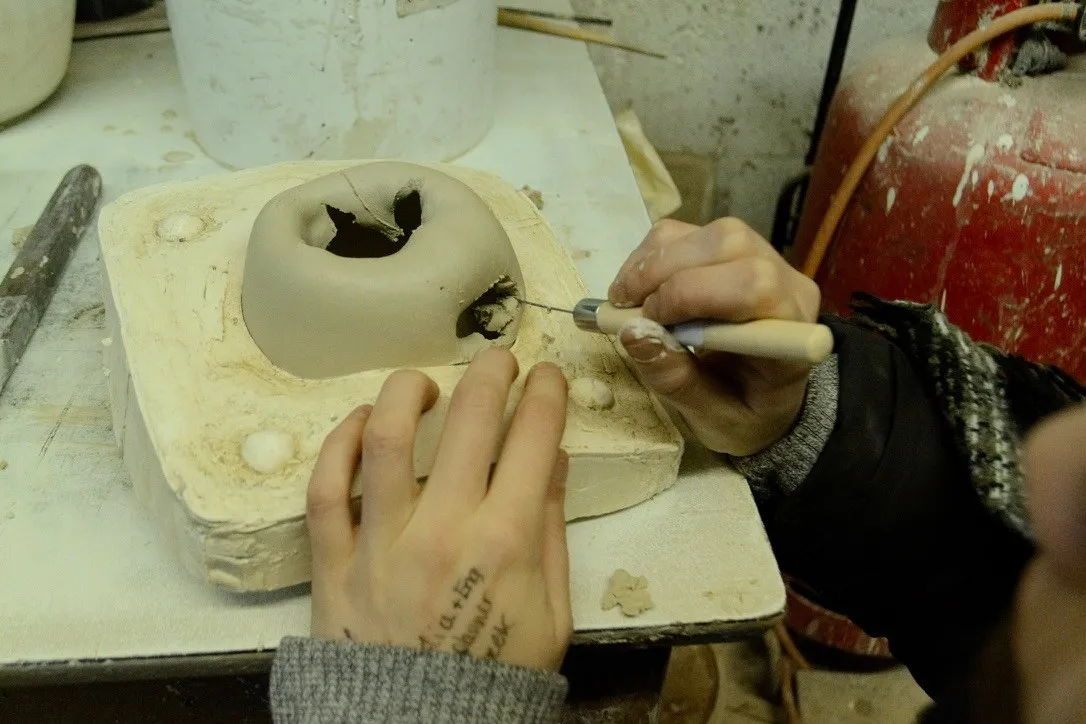 A small brush being used to add glaze to a white ceramic apple.