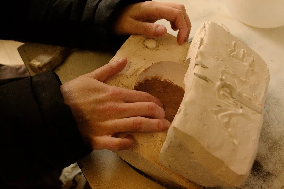 Hands working with a mould around an apple form.