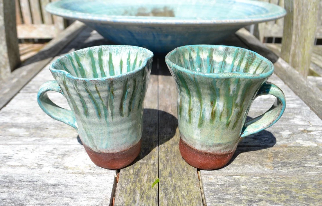 Two turquoise glazed fungi mugs with irregular rims and brown bases.