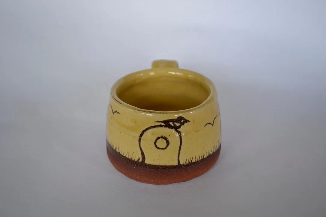 Yellow mug showing the holed stone at Mên an Tol and neighbouring standing stones.
