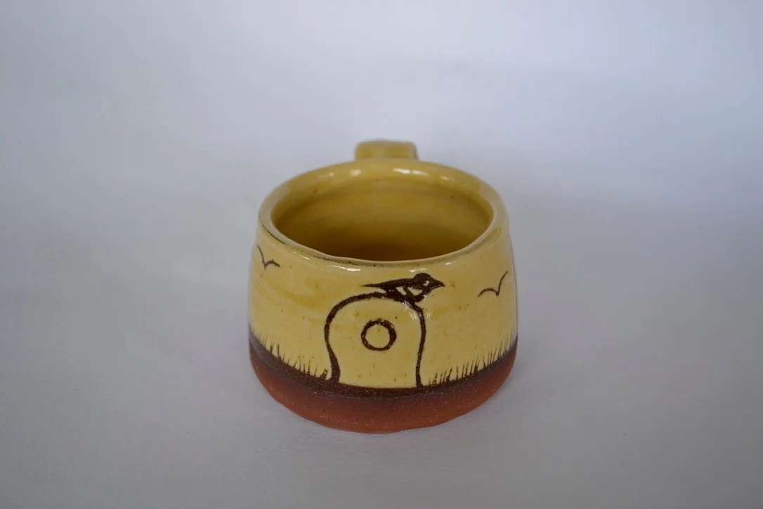 Yellow mug showing the holed stone at Mên an Tol and neighbouring standing stones.