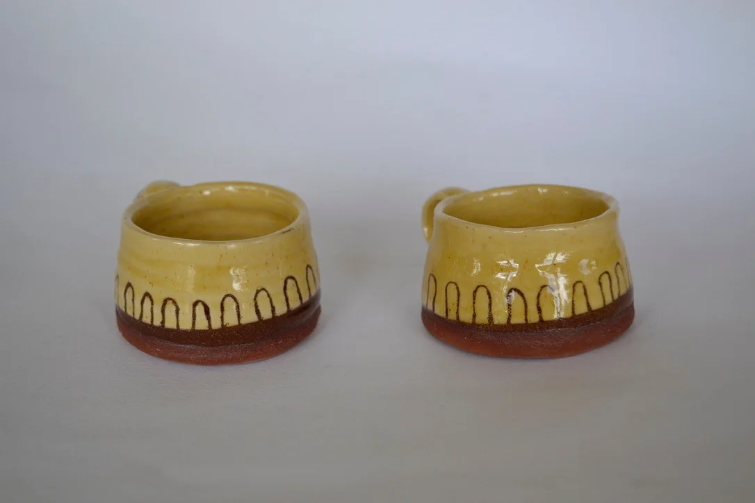 Another view of the yellow standing-stone mugs with their curved handles.